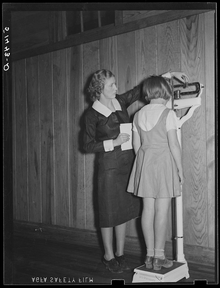 Nurse, Miss Teal, weighing child in health room of Goodman School. Coffee County, Alabama. Sourced from the Library of…