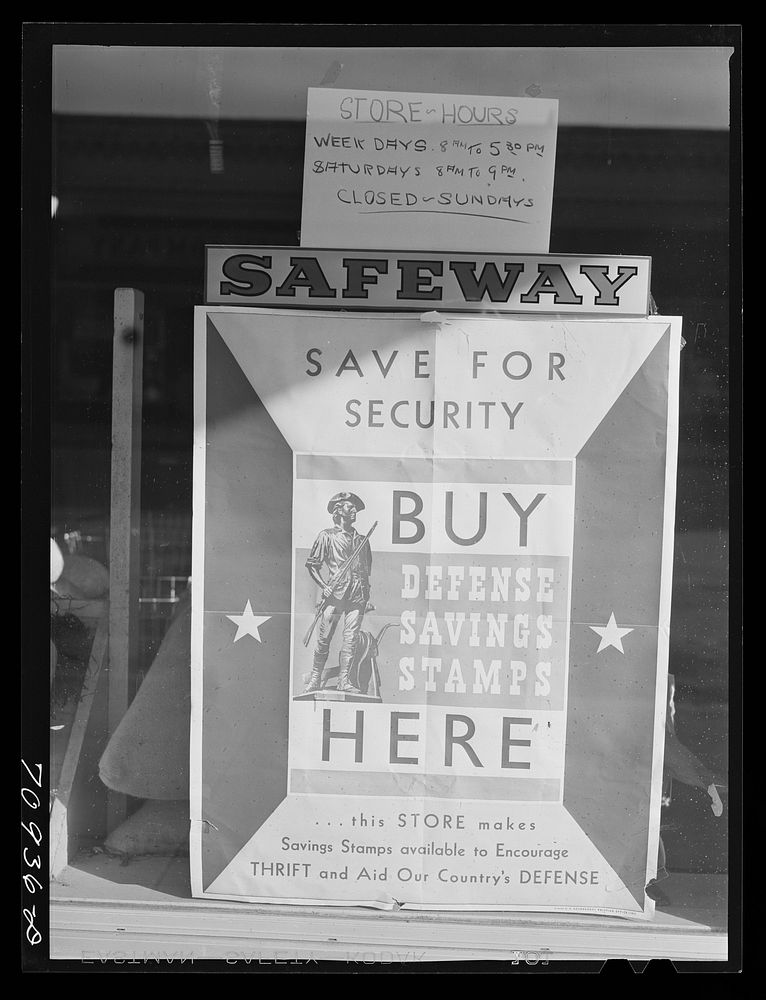 Defense saving stamps sign on grocery store. Payette, Idaho by Russell Lee