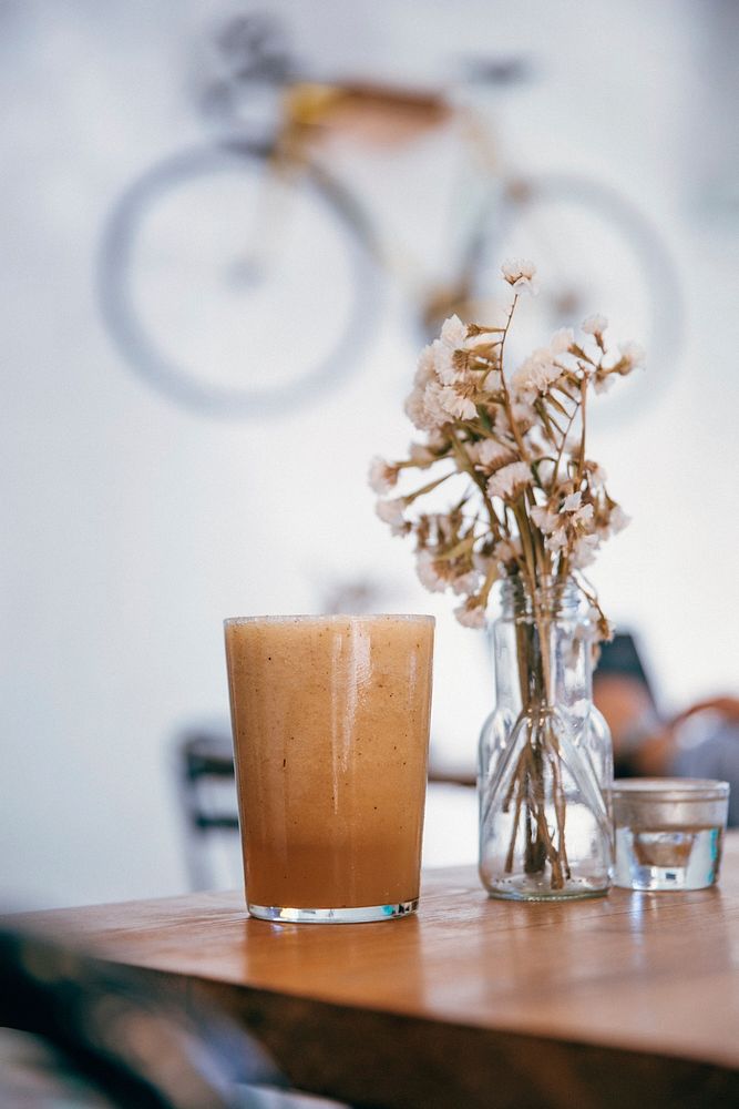 Free smoothie glass with vase on wooden table photo, public domain beverage CC0 image.