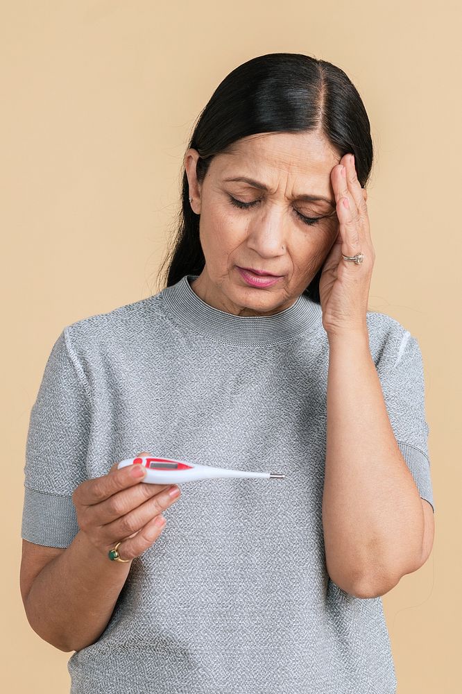 Indian woman with a headache measuring her temperature with an electric thermometer 