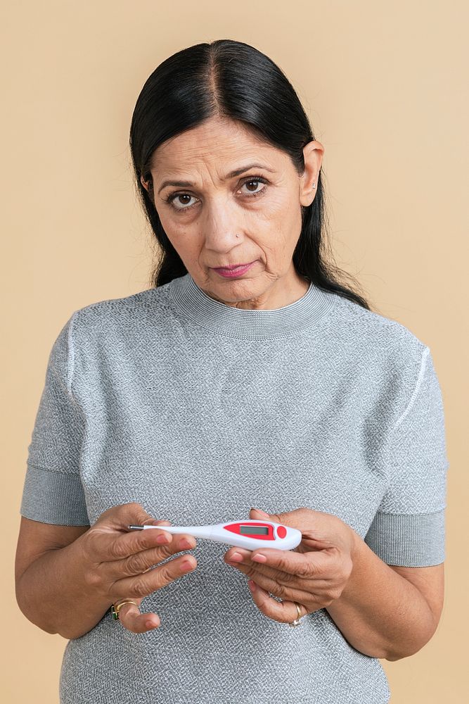 Indian woman measuring her temperature with an electric thermometer 