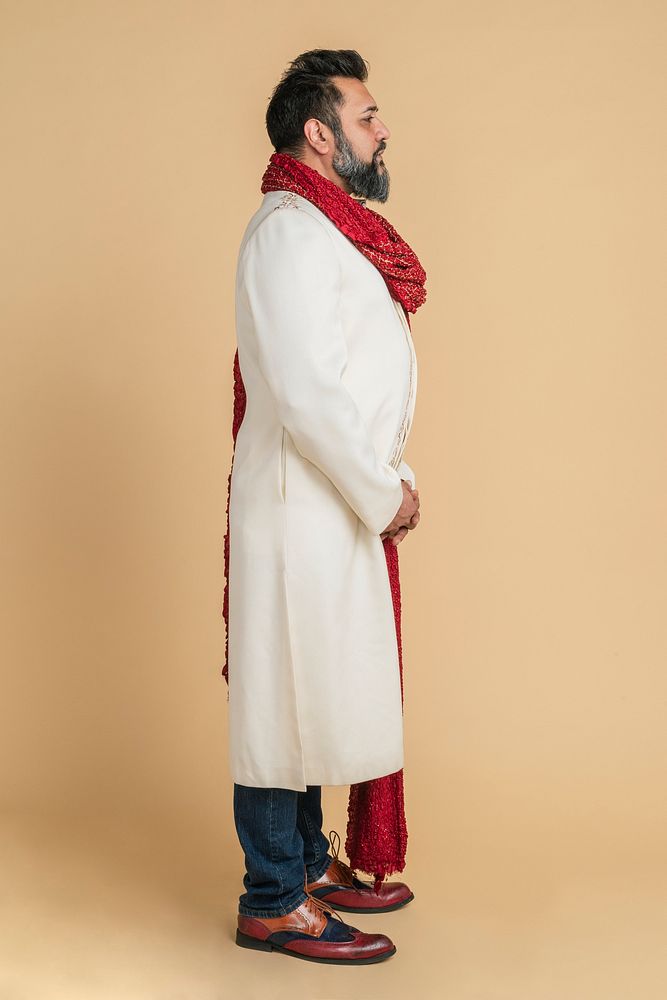 Indian man wearing a kurta with a red scarf in a profile shot 