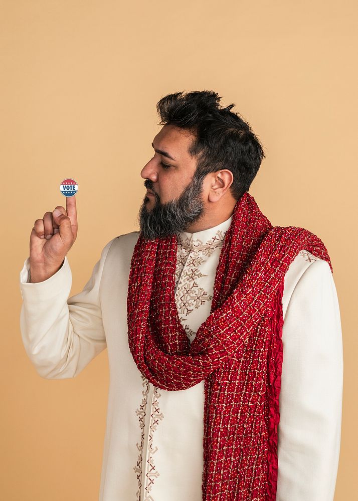 Indian man in a kurta showing a vote sticker