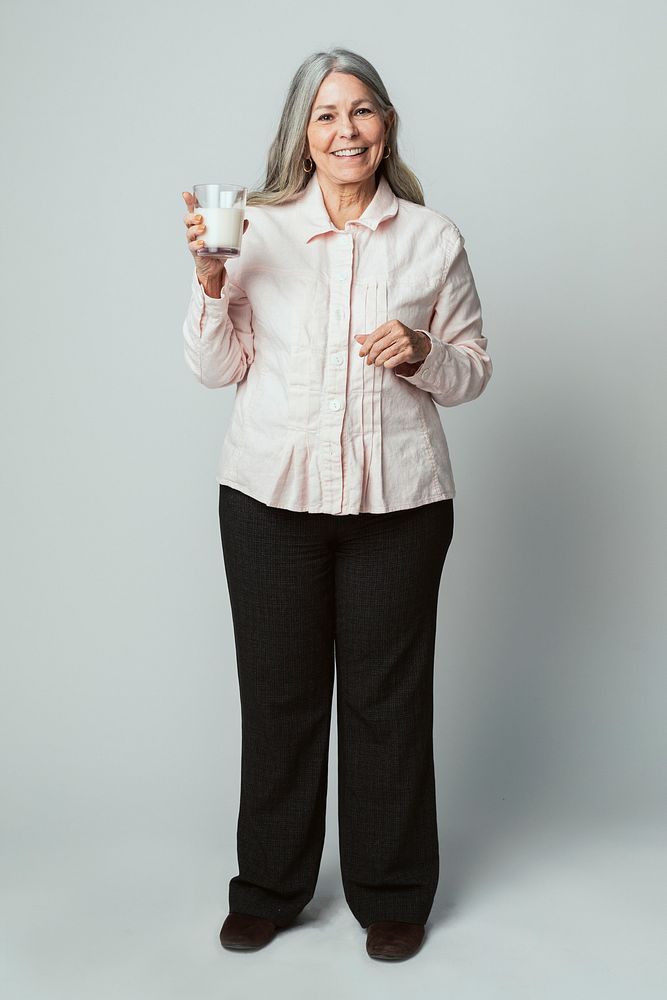 Cheerful senior woman drinking a glass of milk
