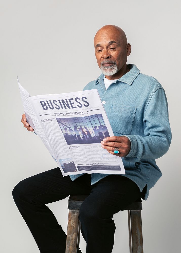 Black man on a stool reading a newspaper