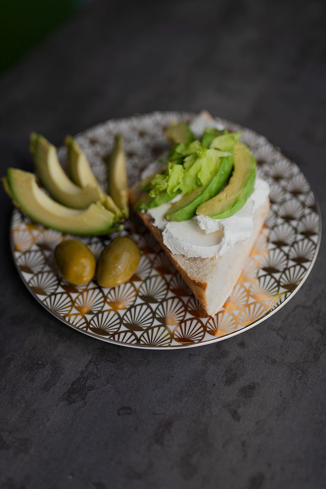 Healthy avocado toast serves on a modern patterned plate with olives