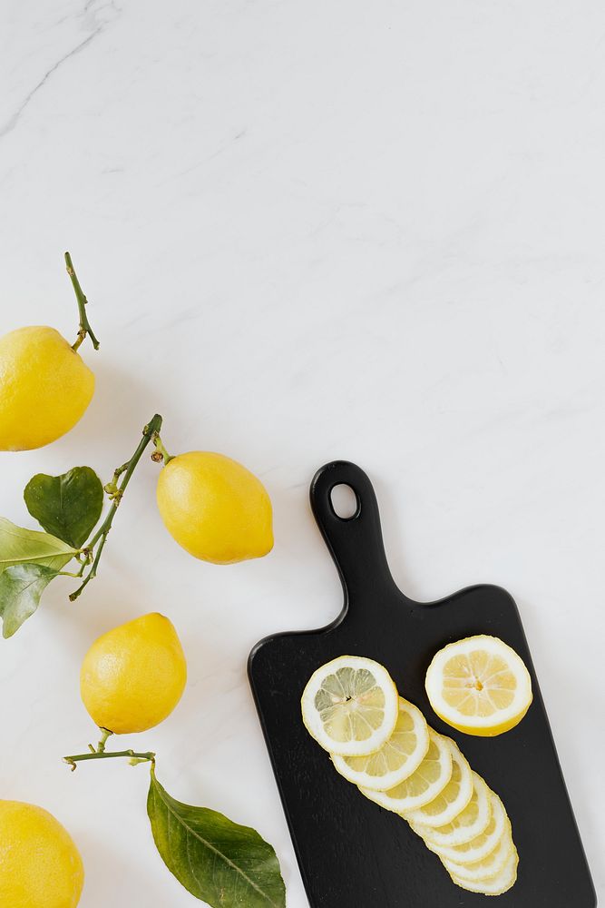 Fresh slices of lemon on a black chopping board flatlay