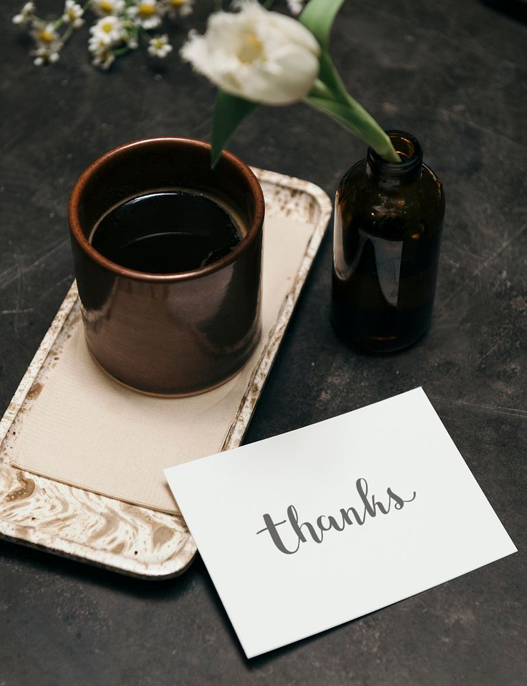 Thank you card beside a warm tea glass