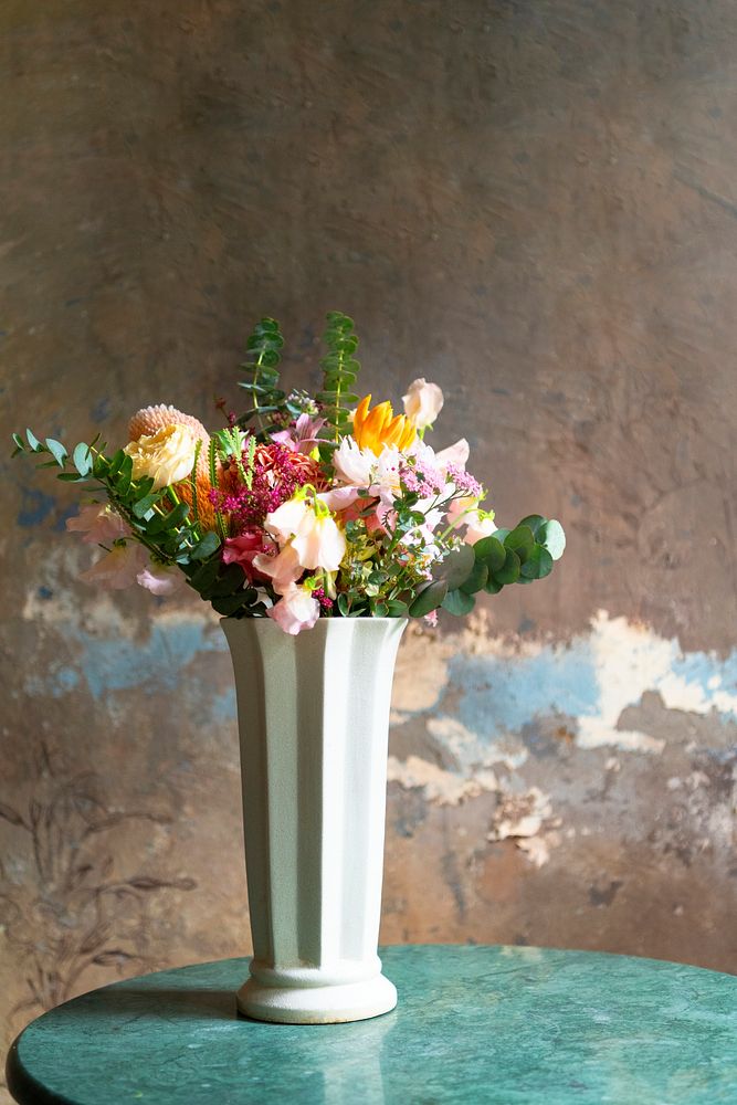 Flowers in a vase by a yellow wall