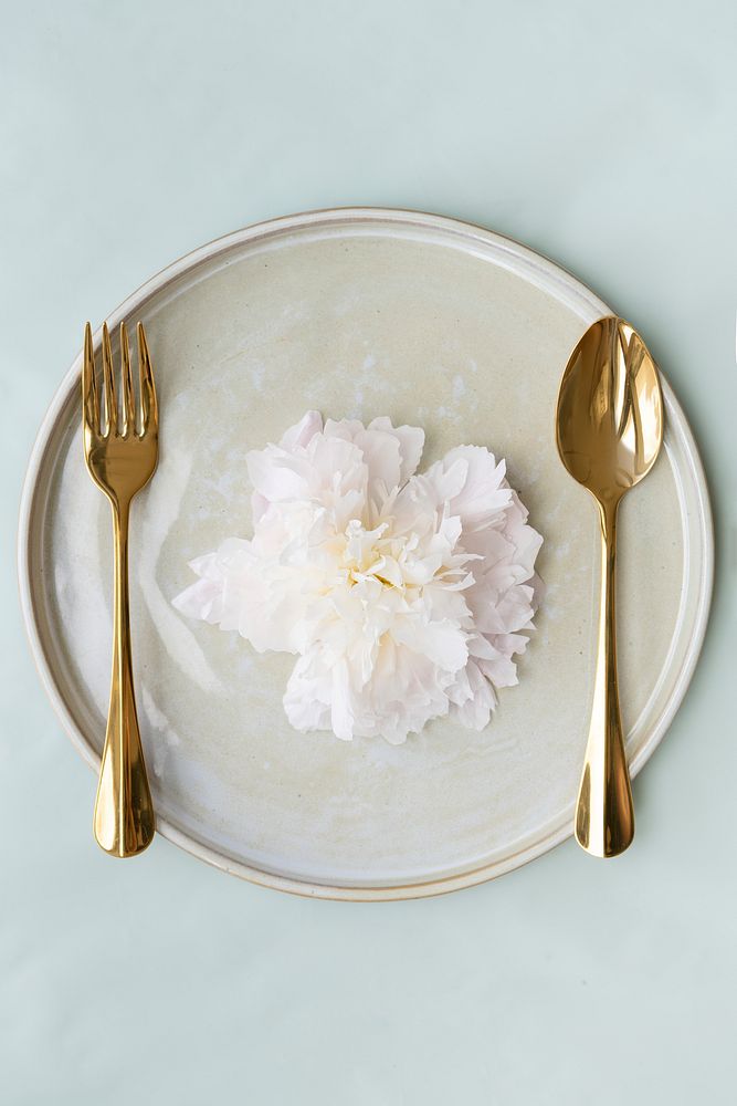 Beautiful flower on a plate with golden spoon and fork