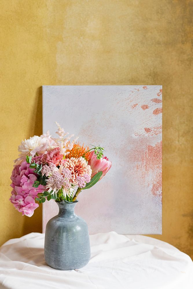 Blank board mockup against a yellow wall by a vase of flowers