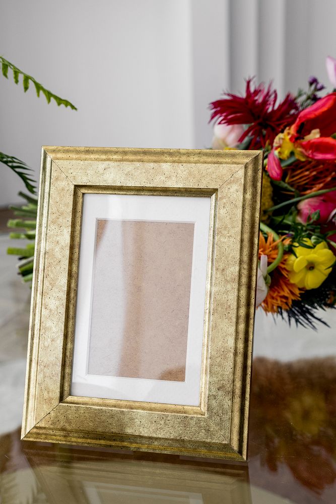Blank golden frame mockup by colorful flowers