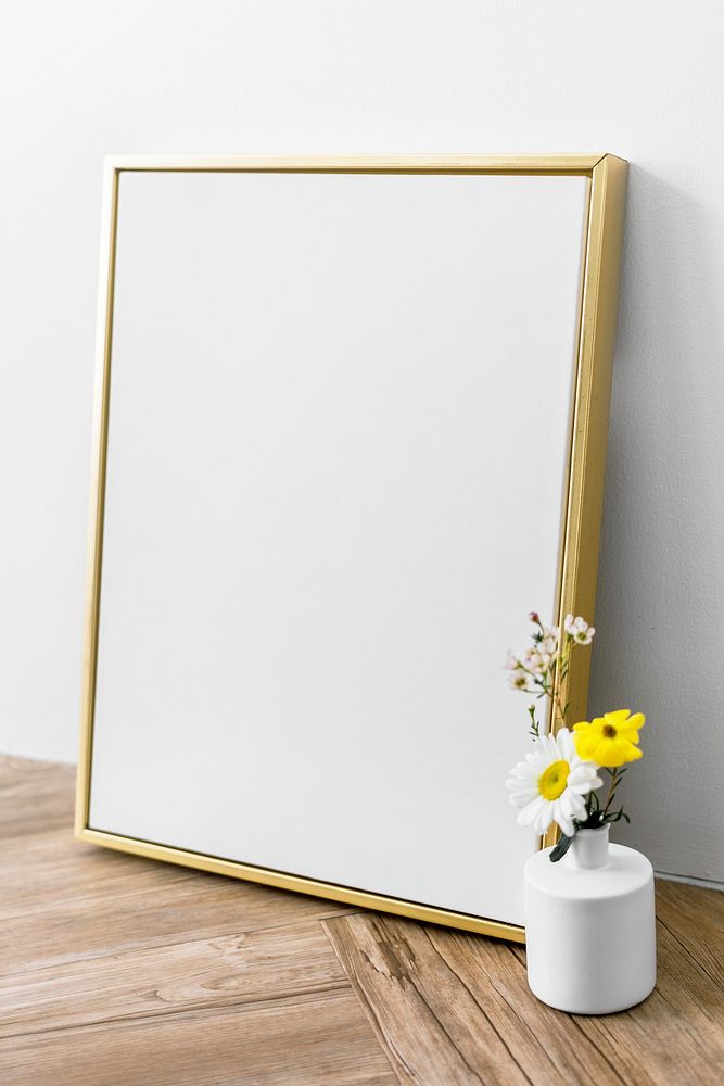 Blank golden frame mockup by a vase of flowers