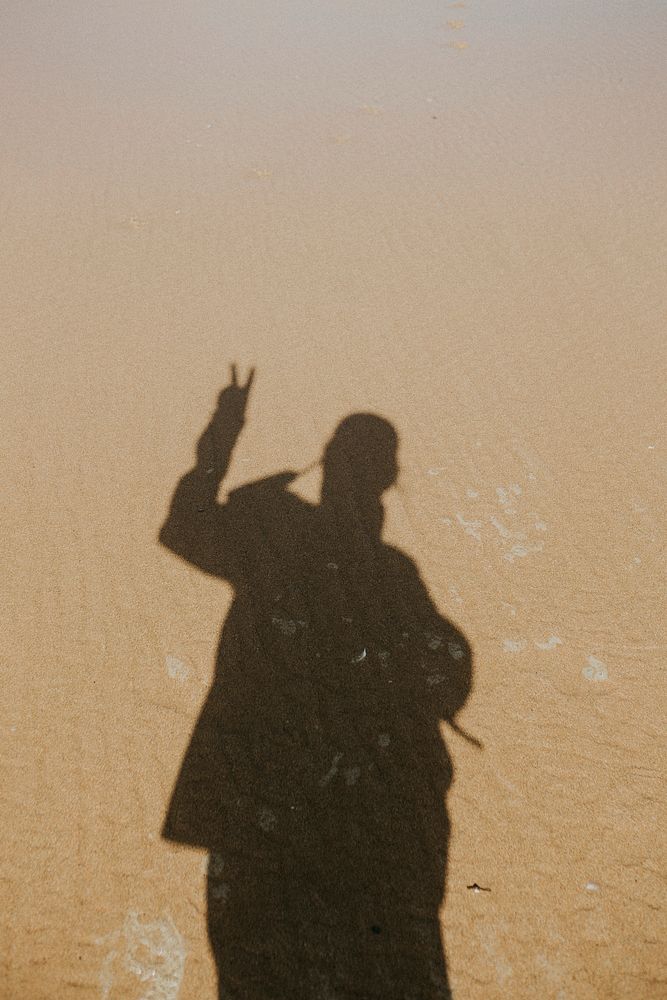 Calm waters over the sand with a shadow of a man