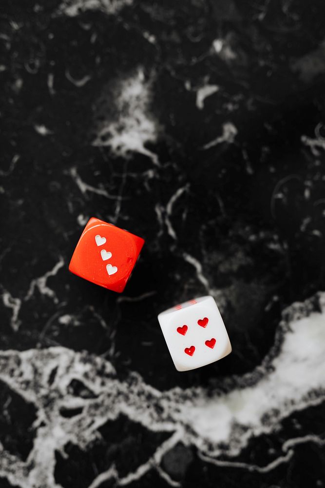 Two heart dices on a black marble background