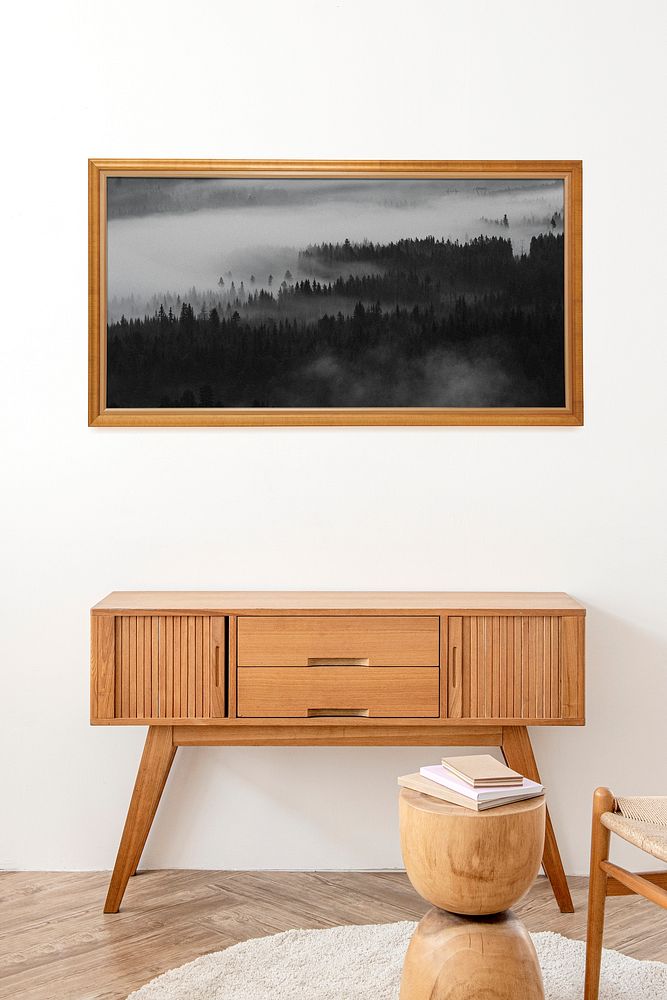Picture frame mockup above a wooden sideboard table 