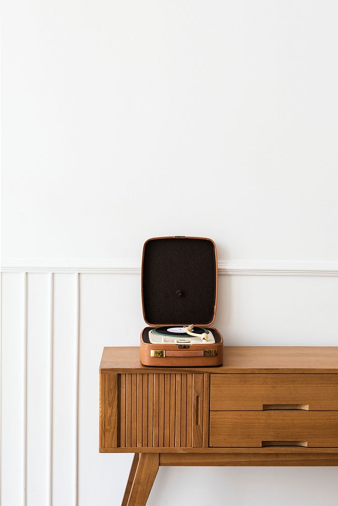 Vinyl player in a portable turntable on a wooden sideboard table 