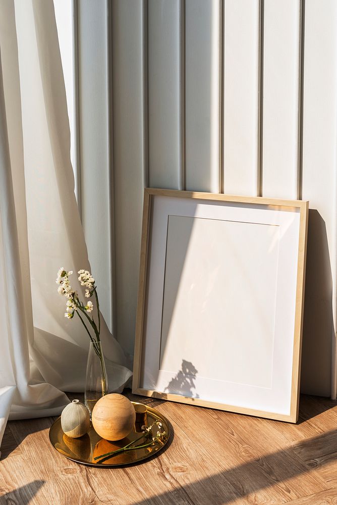 Blank picture frame by a white wall on the wooden floor