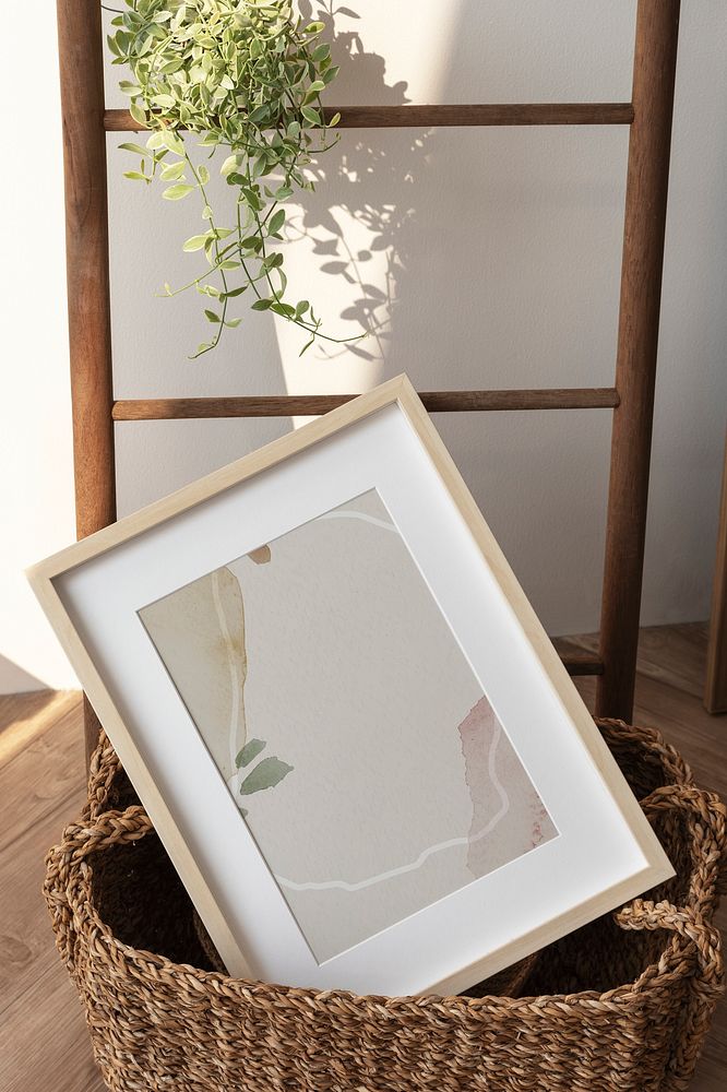 Picture frame mockup in a wicker basket by the wooden ladder 