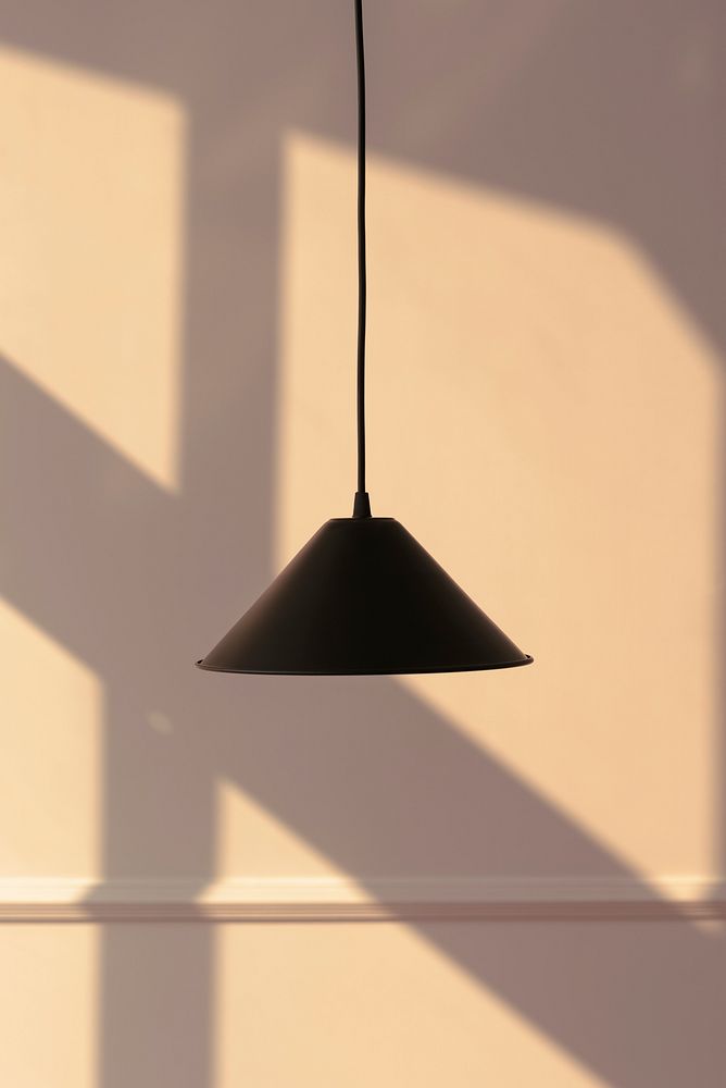 Black pendant lamp with a late afternoon light on a beige wall