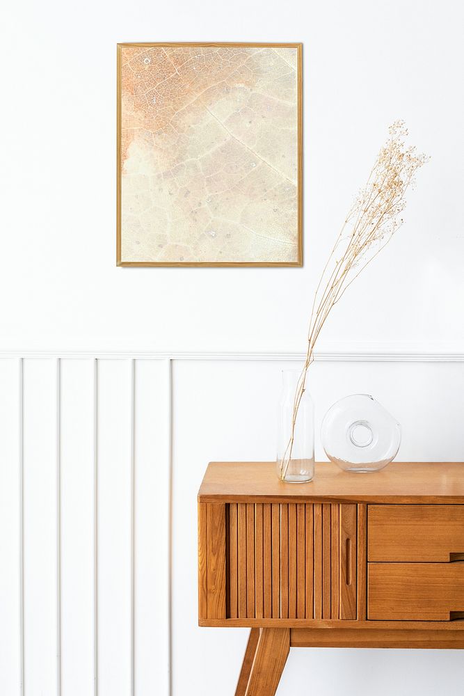 Picture frame mockup above a wooden sideboard table with dried flowers in a vase 