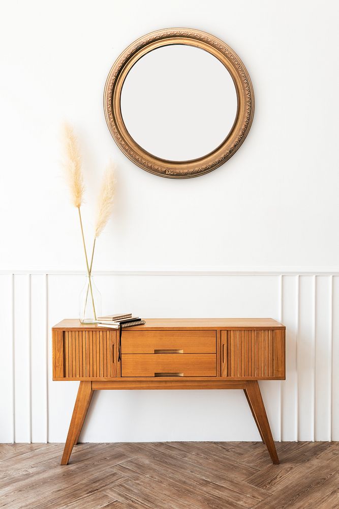 Mirror over a wooden sideboard table with dried pampas grass in a vase