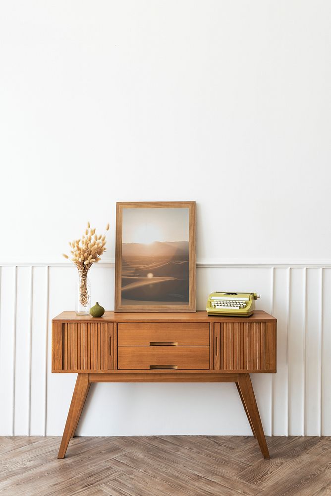 Picture frame mockup on a wooden sideboard table with hare's tail grass and a typewriter 
