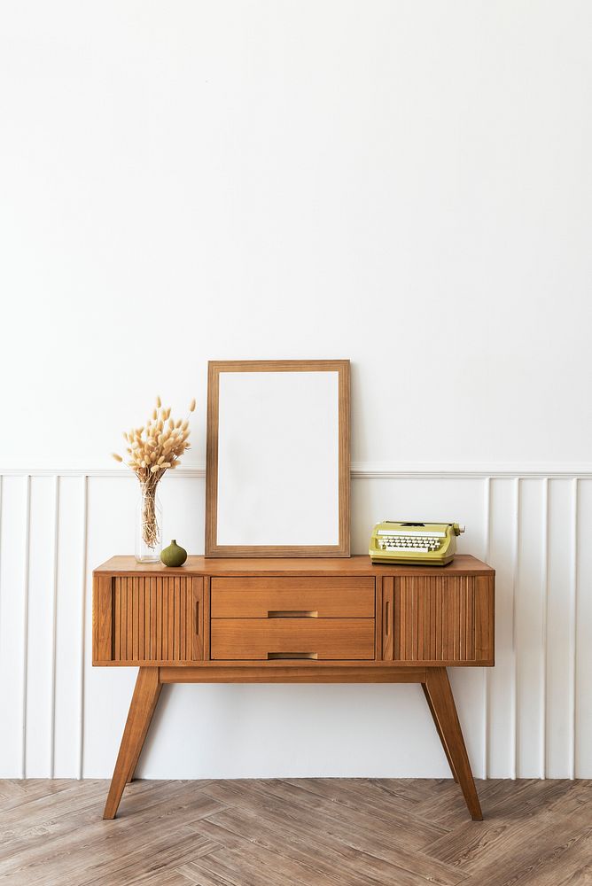 Picture frame on a wooden sideboard table with hare's tail grass and a typewriter