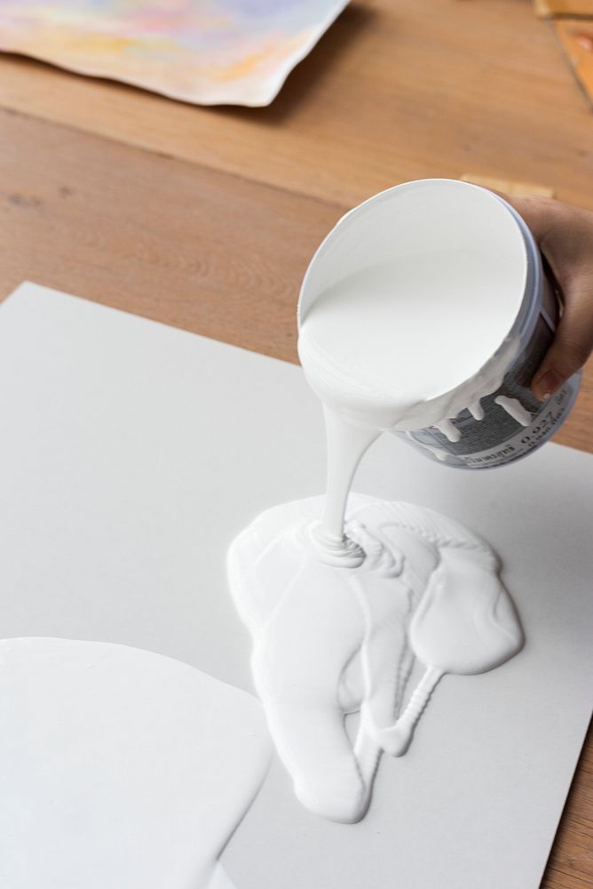 Artist pouring white acrylic paint art technique