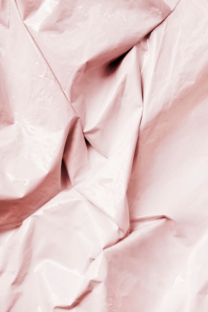 Pastel pink crumpled plastic textured textile background