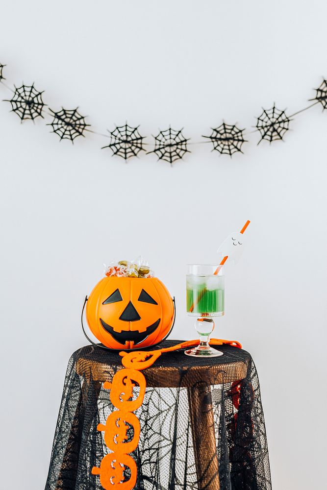 Halloween drink and a pumpkin basket filled with sugar candies on a table 