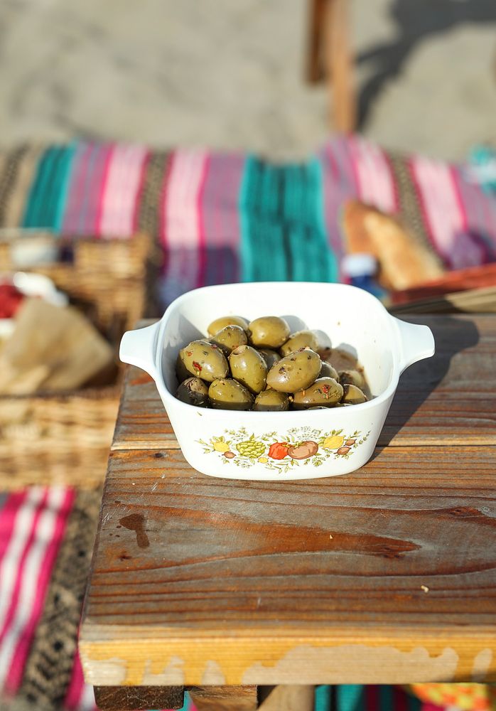 Spicy pickled olives in a white bowl at a beach picnic