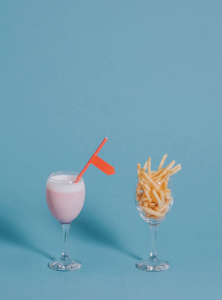 French fries in a wine glass beside a pink drink