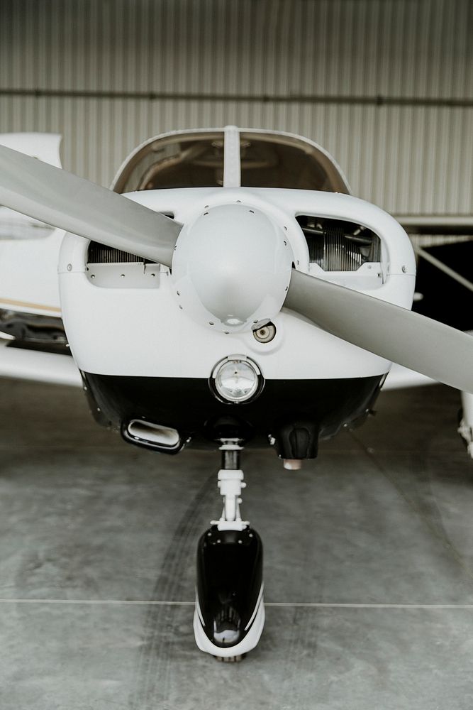Front propellor plane parked in a hangar