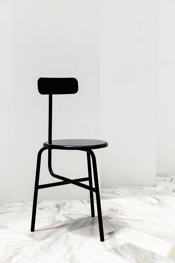 A black modern chair on a white marble floor