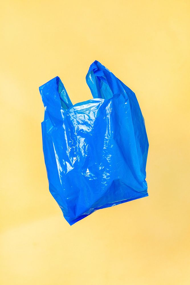 Blue plastic bag floating with a yellow wall