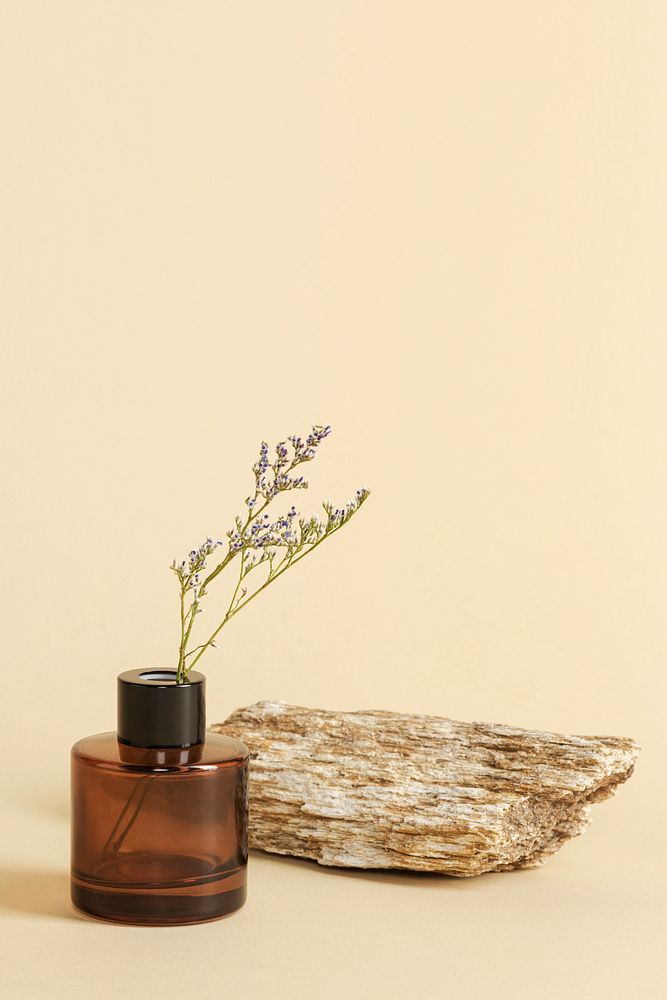 Dried grass flower in a brown bottle by a stone