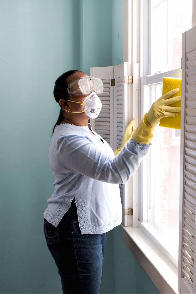 Woman using a damp sponge to clean dust collected on a window sill. Original image sourced from US Government department:…