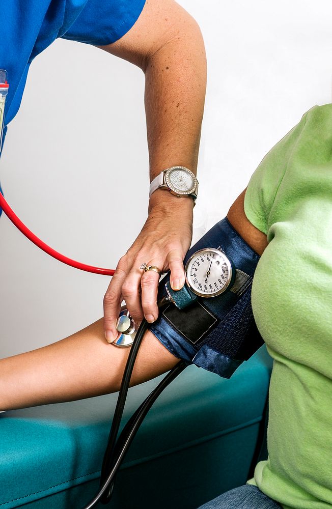Female clinician in the process of conducting a blood pressure examination on a patient. Original image sourced from US…