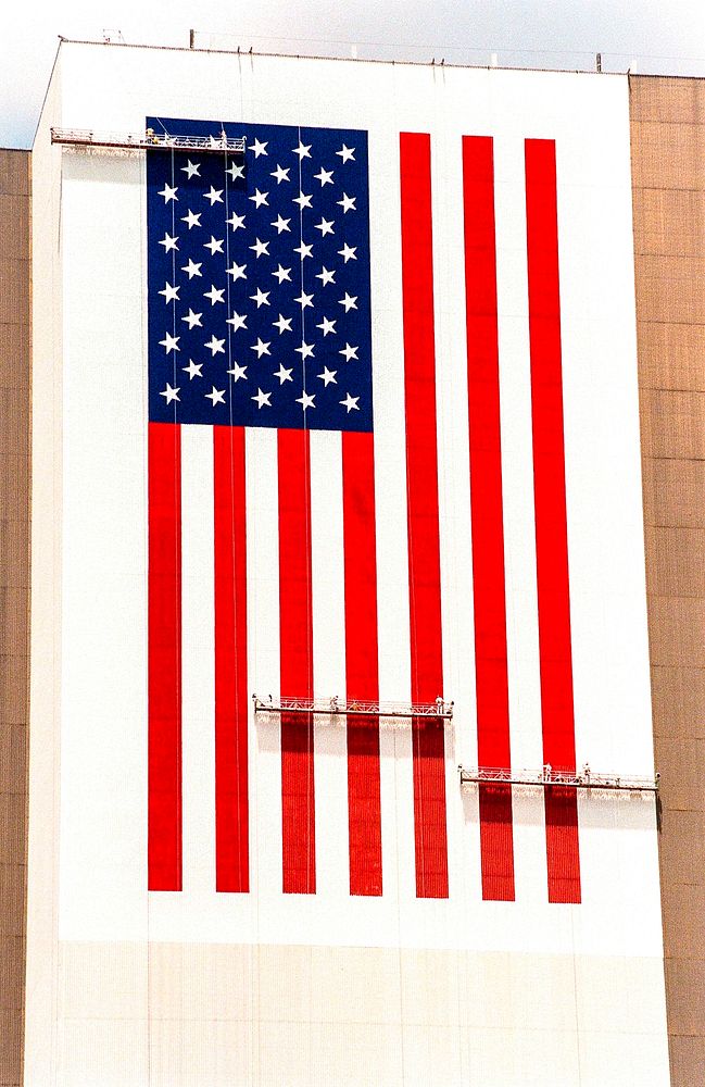 The American flag is being repainted on the side of the Vehicle Assembly Building. Original from NASA. Digitally enhanced by…