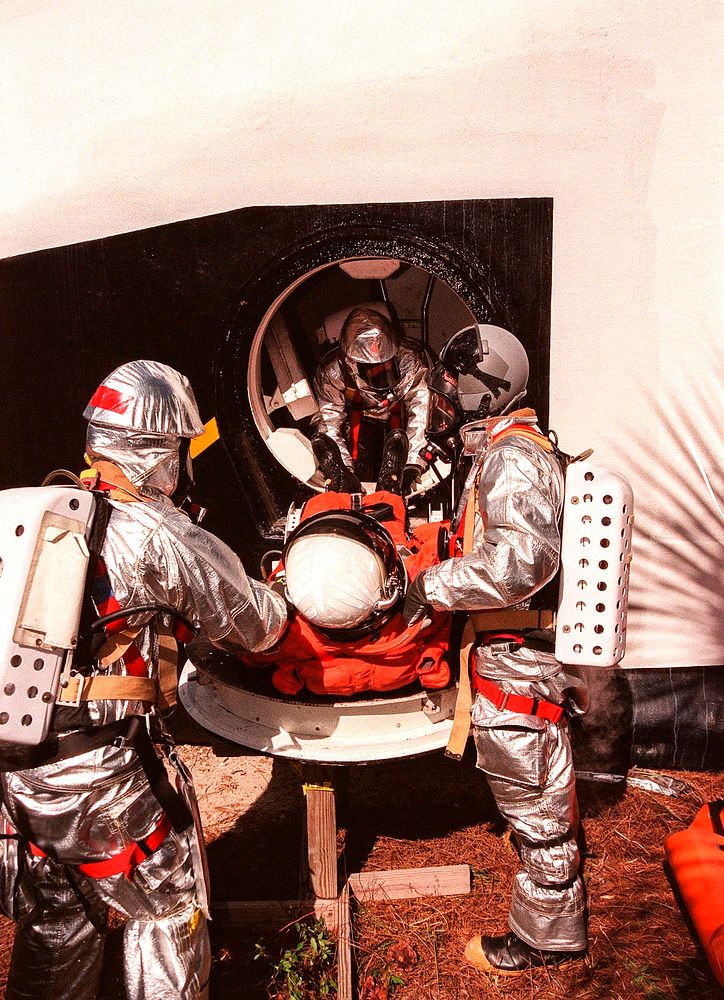 During a simulated rescue mission the KSC response team removes a Shuttle crew member from the mock orbiter. Original from…