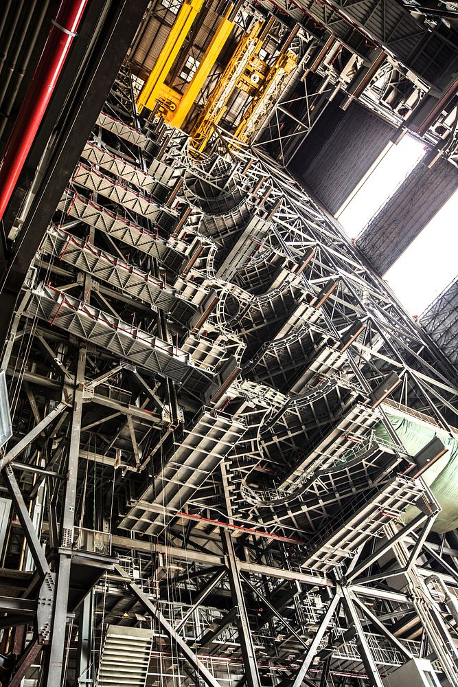 High up in the Vehicle Assembly Building (VAB) at NASA's Kennedy Space Center in Florida, a crane lowers the second half of…