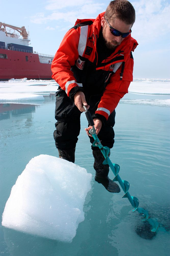 Dartmouth College's Chris Polashenski cuts a block of ice from below a melt pond on sea ice in the Chukchi Sea on July 9…