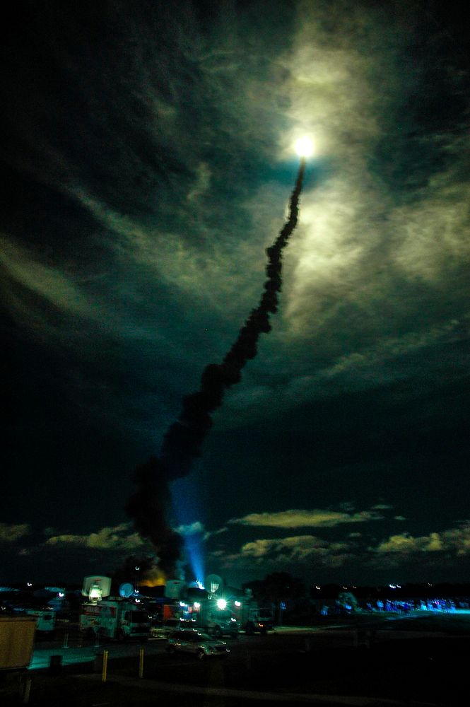 Flooding the night sky with light, Space Shuttle Discovery streaks through the clouds after liftoff from Launch Pad 39B on…