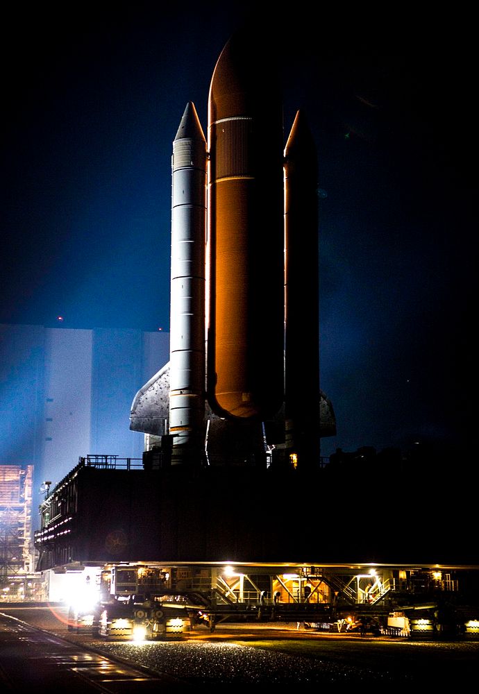 Xenon lights illuminate space shuttle Discovery as it makes its nighttime trek, known as rollout, from the Vehicle Assembly…