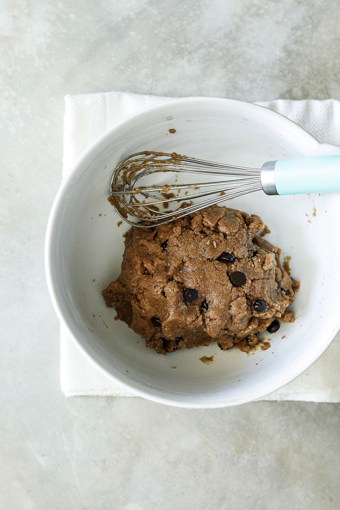 Chocolate chip cookie dough in a bowl with whisk