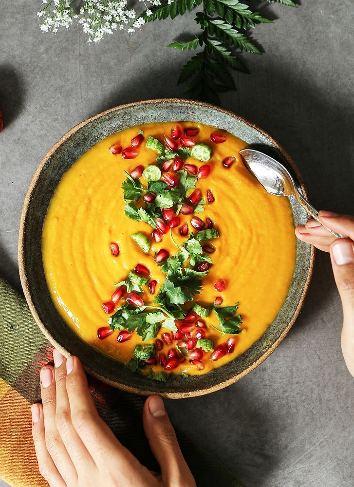 Fresh pumpkin soup topped with parsley and pomegranate seeds