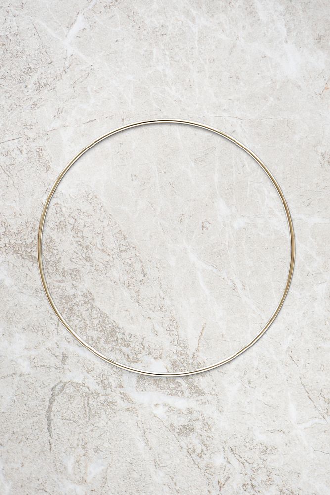 Round gold frame on beige marble background