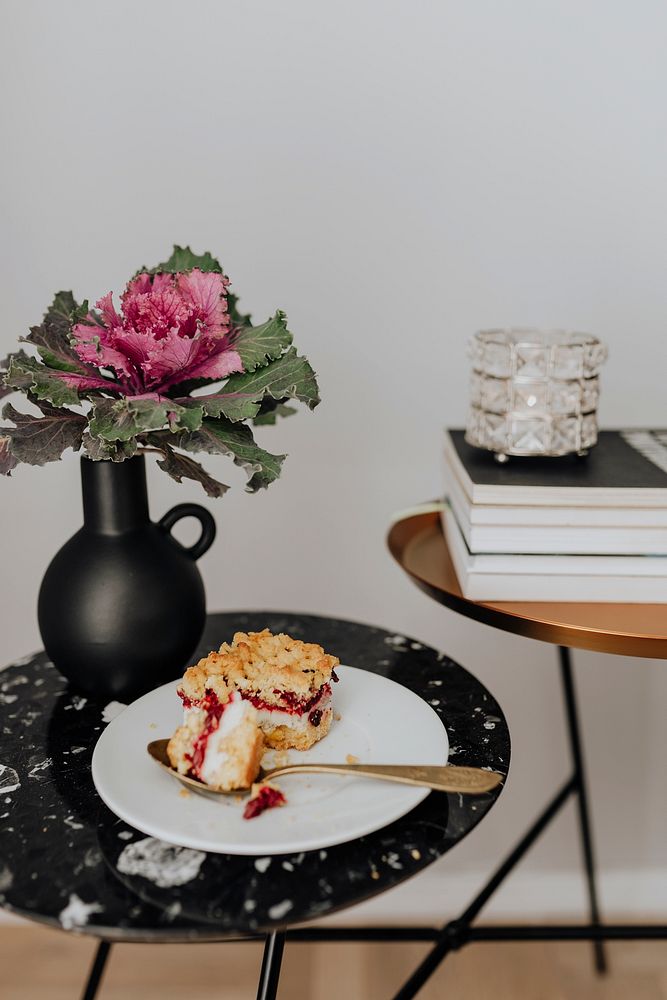 Slice of cheesecake next to an ornamental kale on a black table