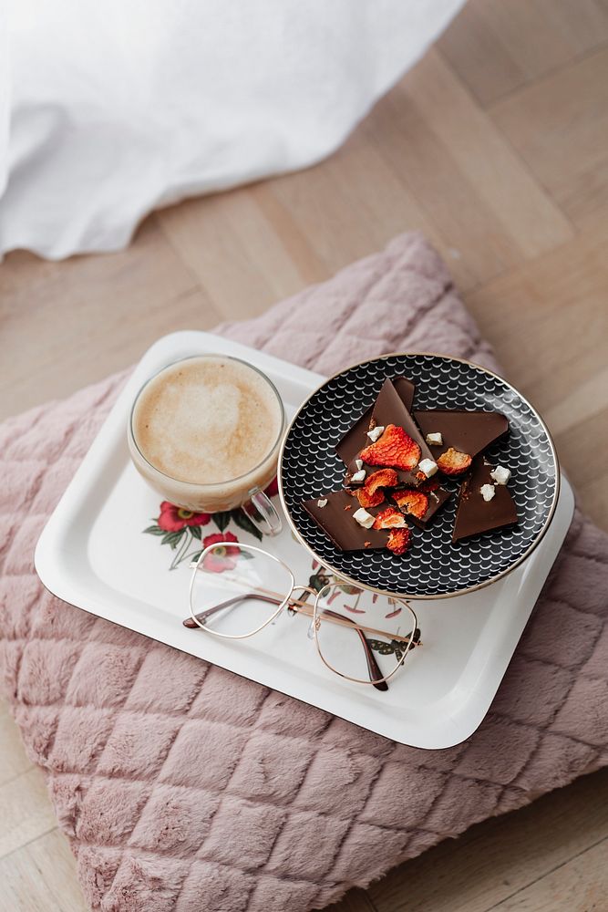Dark chocolate brittle with strawberry served with coffee on a pink cushion